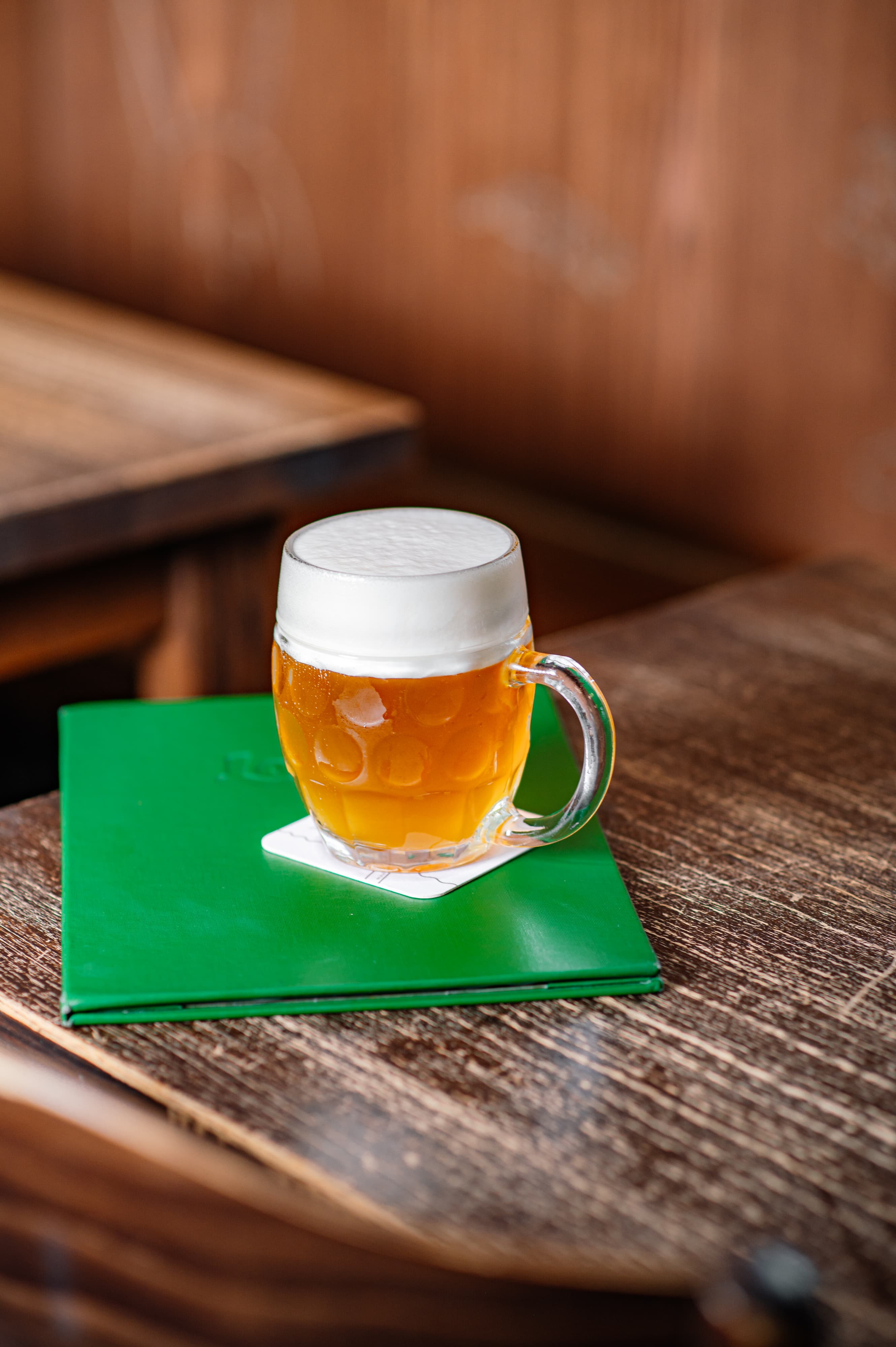ůllitr nefiltrovaného Pilsner Urquell s bohatou pěnou postavený na stole v Lokále.