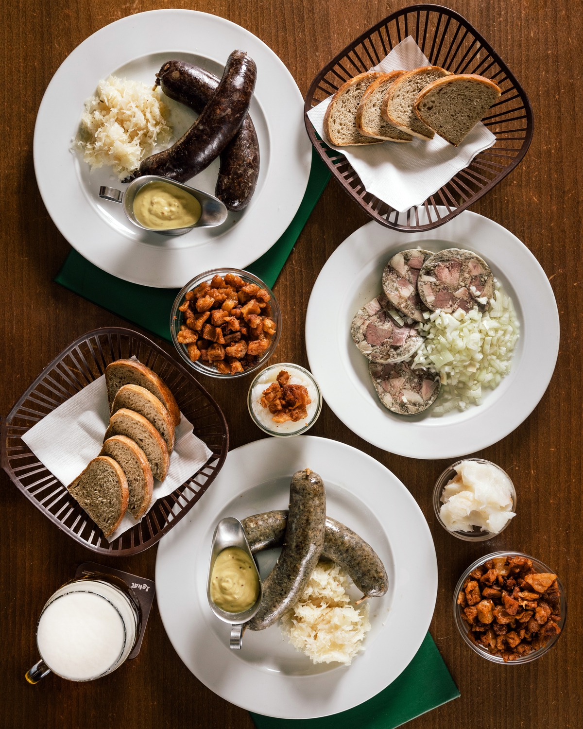 Tradiční české zabijačkové menu na stole – jelita, jitrnice, tlačenka, chléb, škvarky, kysané zelí, hořčice a pivo.