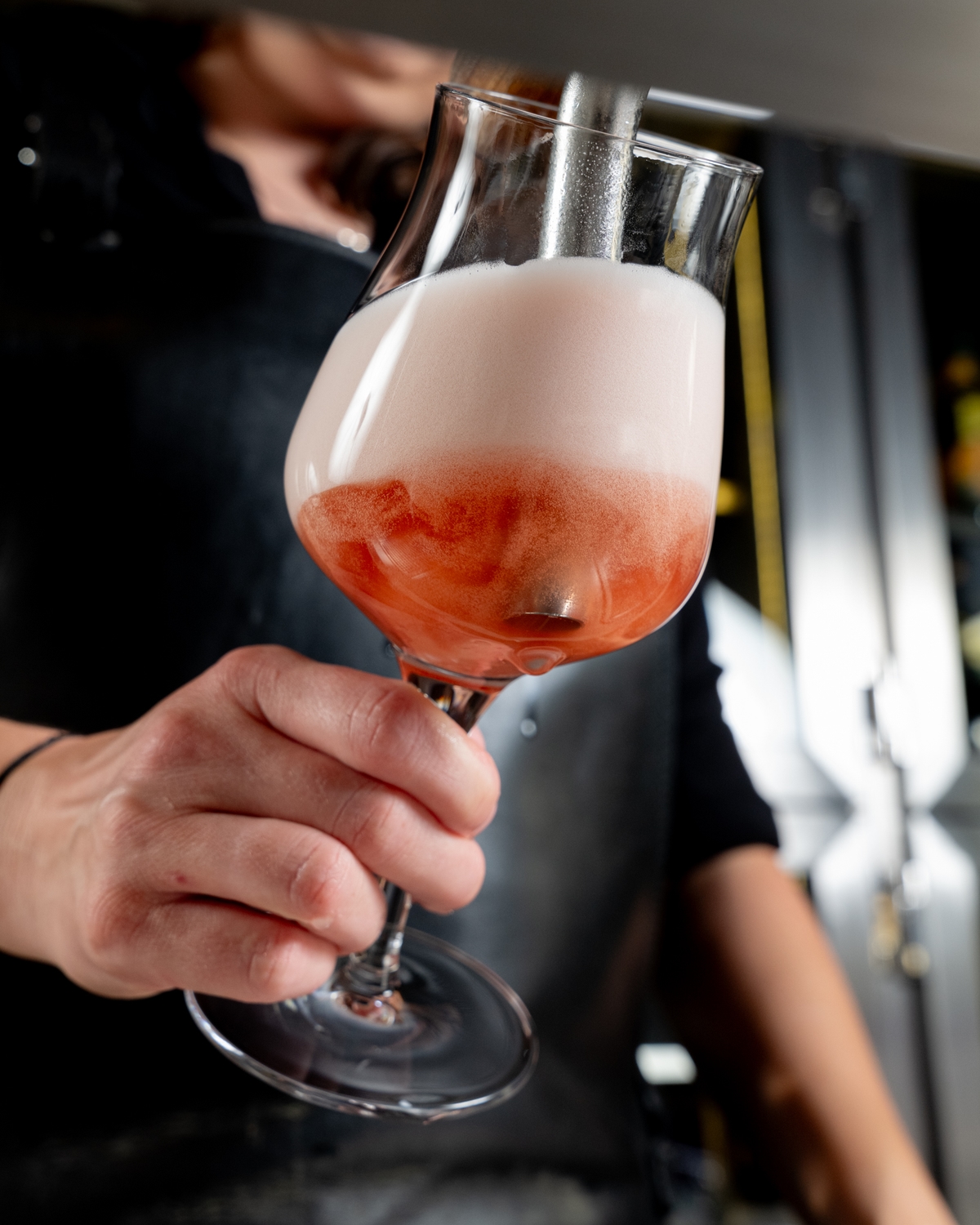 Barmanka čepuje růžově zbarvené pivo s hustou pěnou do sklenice v Pultu.