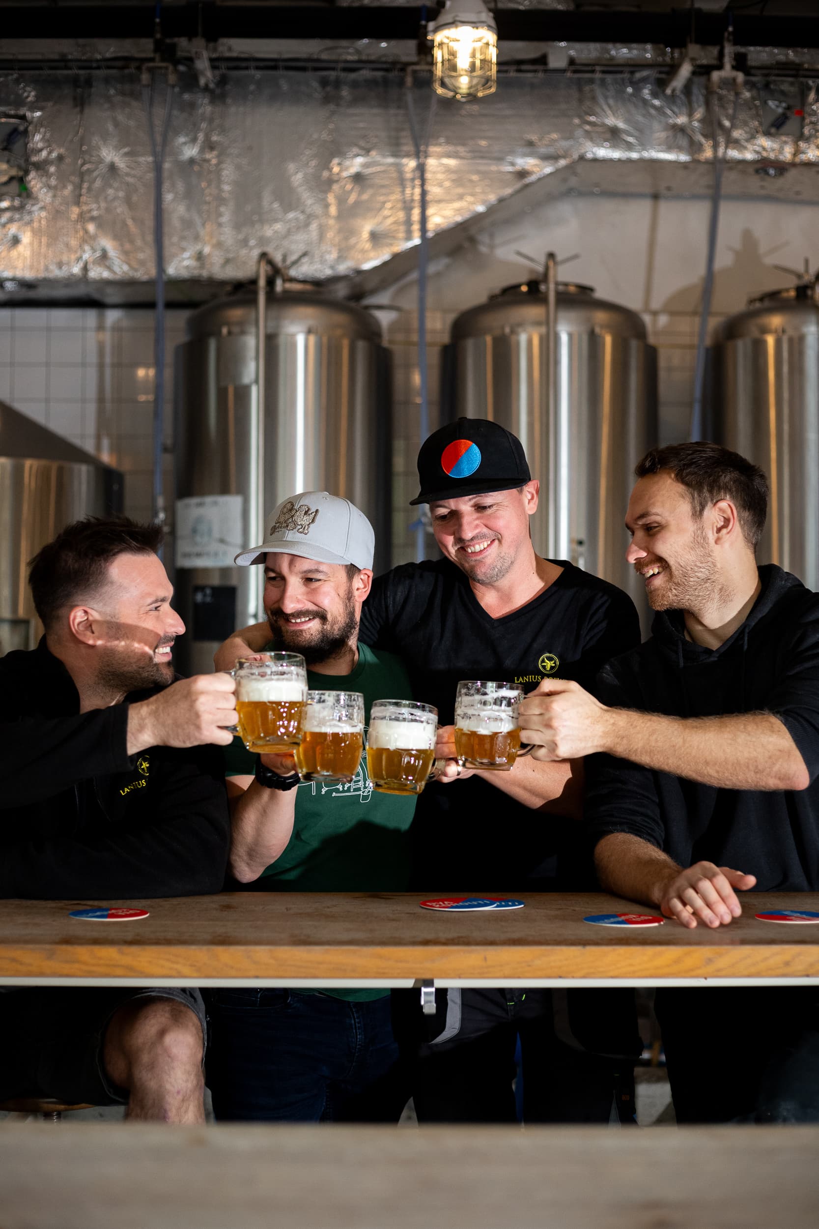 Skupina sládků a přátel si přiťukává půllitry piva v pivovaru Dva kohouti během příprav slovenského pivního mejdanu.